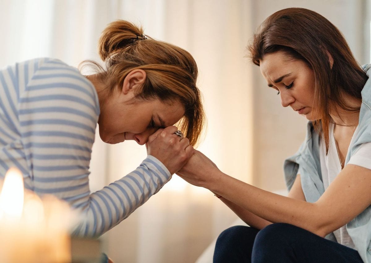 A daughter holding her mother's hands during a difficult conversation at home