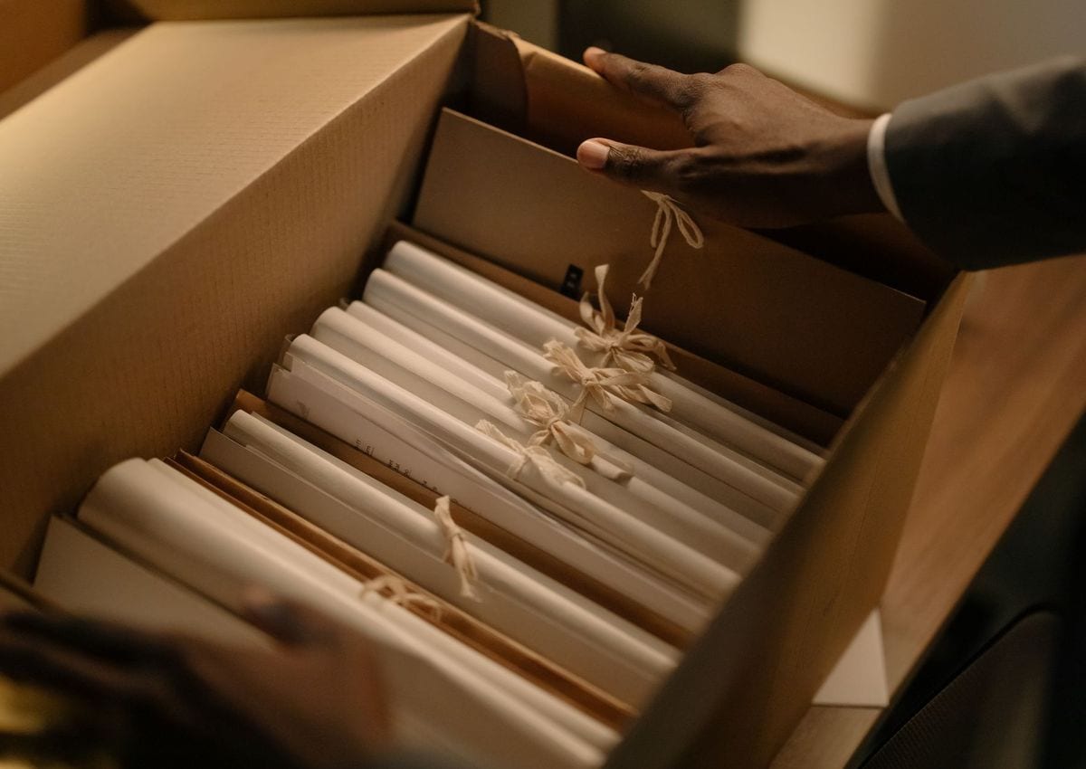 Hands sorting through a box of ribbon-tied legal files